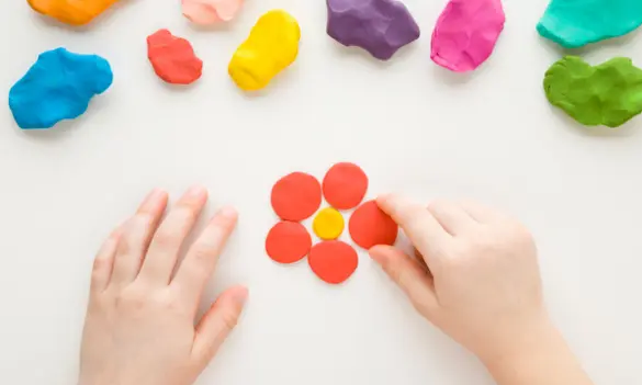 Manos infantiles creando flores con goma EVA y materiales de manualidades