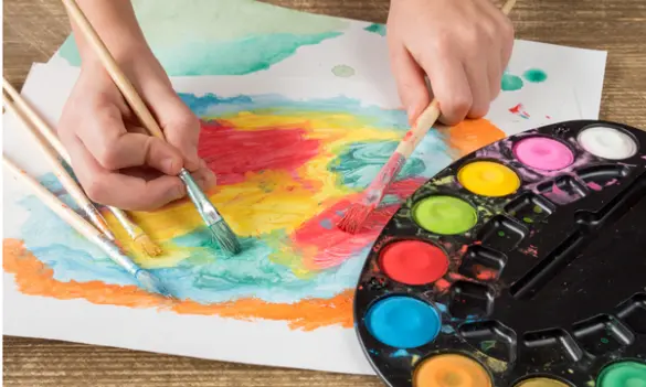 Niños pintando con acuarelas, pinceles y témperas en actividades escolares